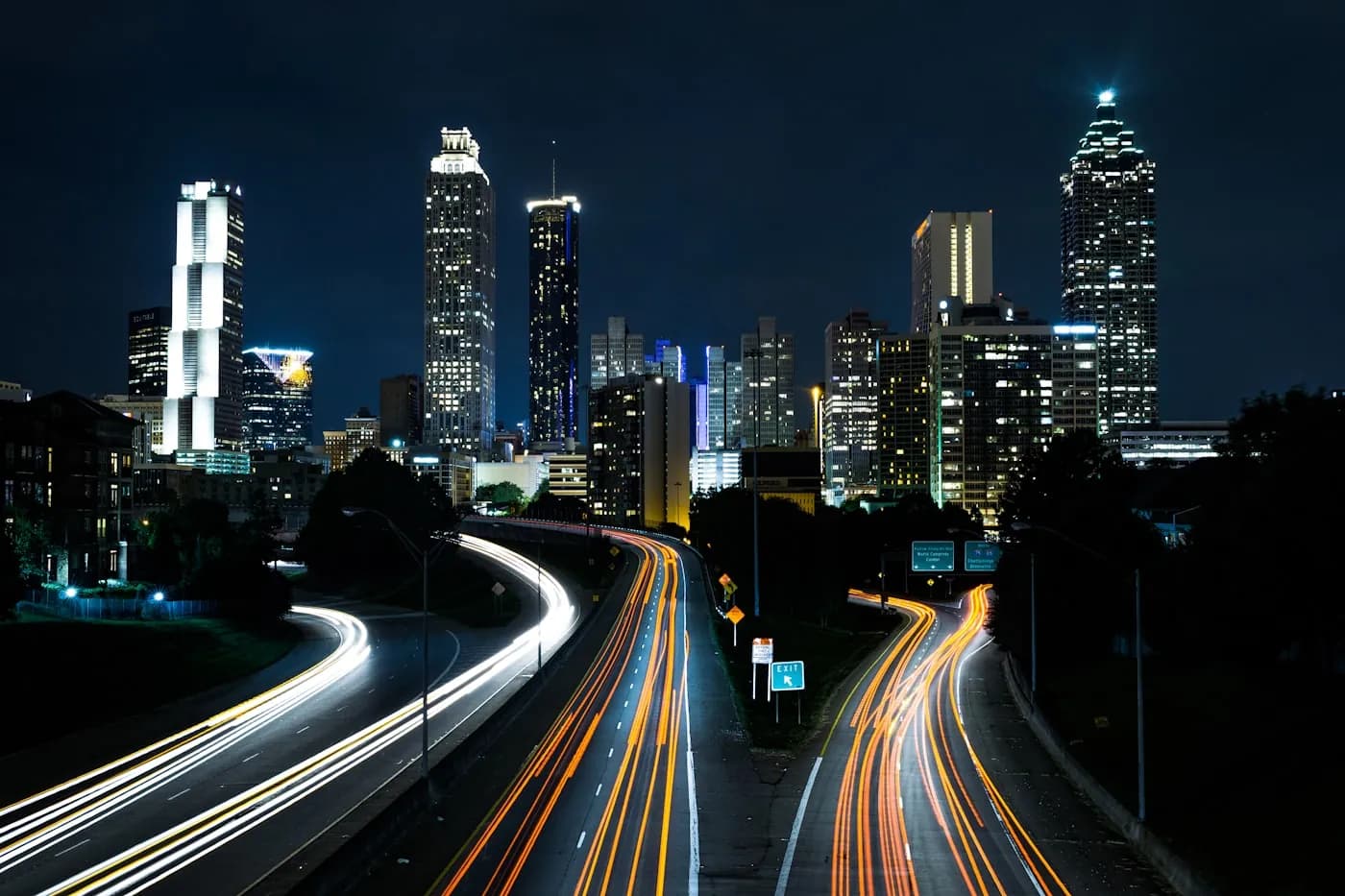 Illuminated highway interchange and modern city at night, representing infrastructure projects